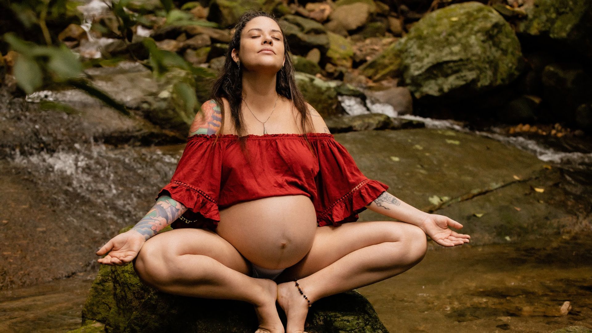 Gestante meditando na cachoeira