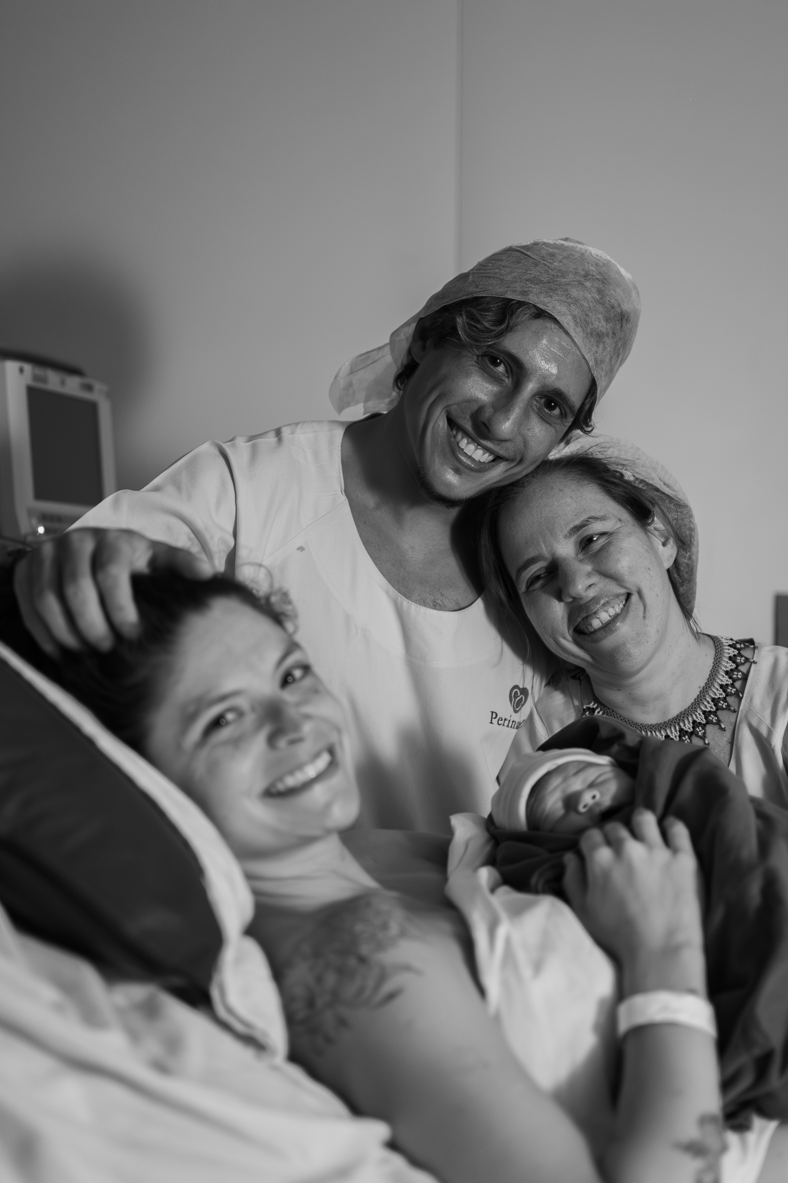 Família sorrindo com recém-nascido e parteira